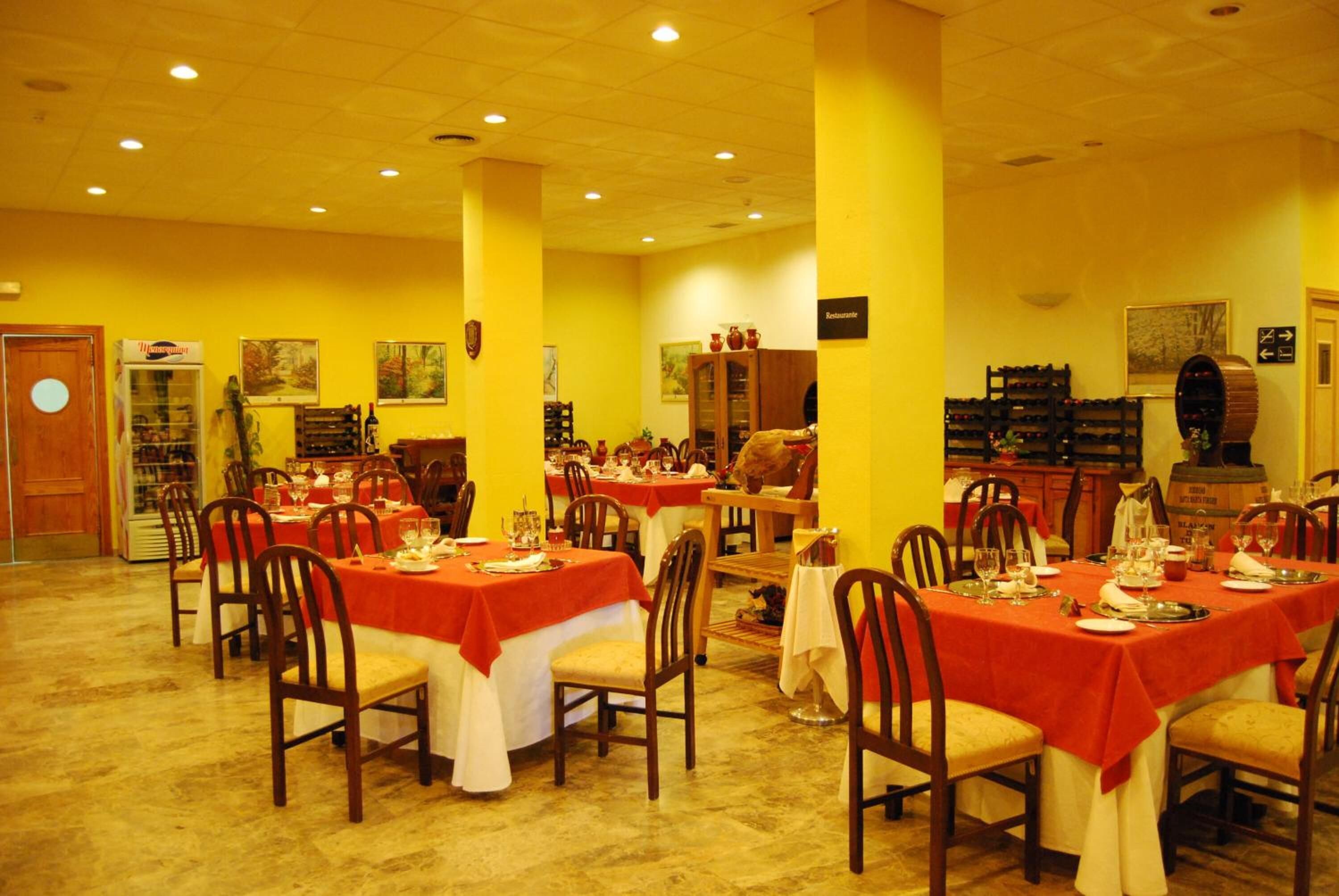 A dining area with multiple tables set for service, chairs, and a variety of dining ware.