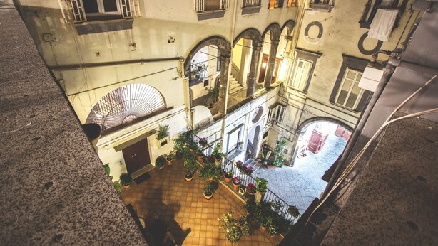 Un patio con macetas, piso de baldosas y una escalera que conduce a un nivel superior.