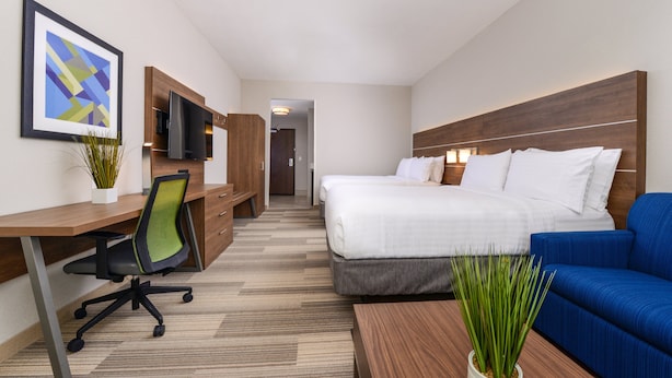 Une chambre d’hôtel avec un lit, un bureau et une chaise, une télévision et un canapé bleu.