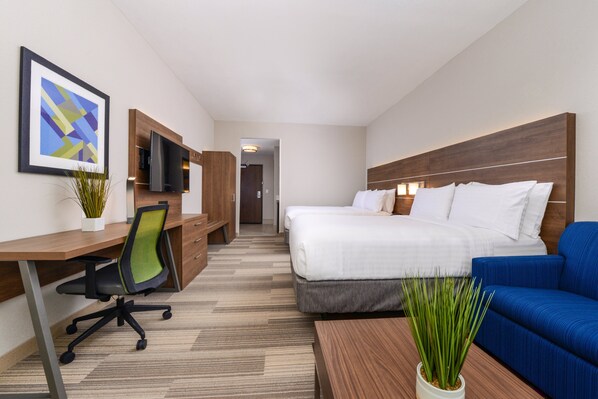 A hotel room with a bed, a desk with a chair, a television, and a blue sofa. - Holiday Inn Express & Suites Alachua - Gainesville Area by IHG (Alachua)