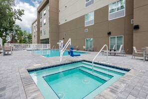 A swimming pool area with a lifeguard stand, lounge chairs, and a white picket fence.