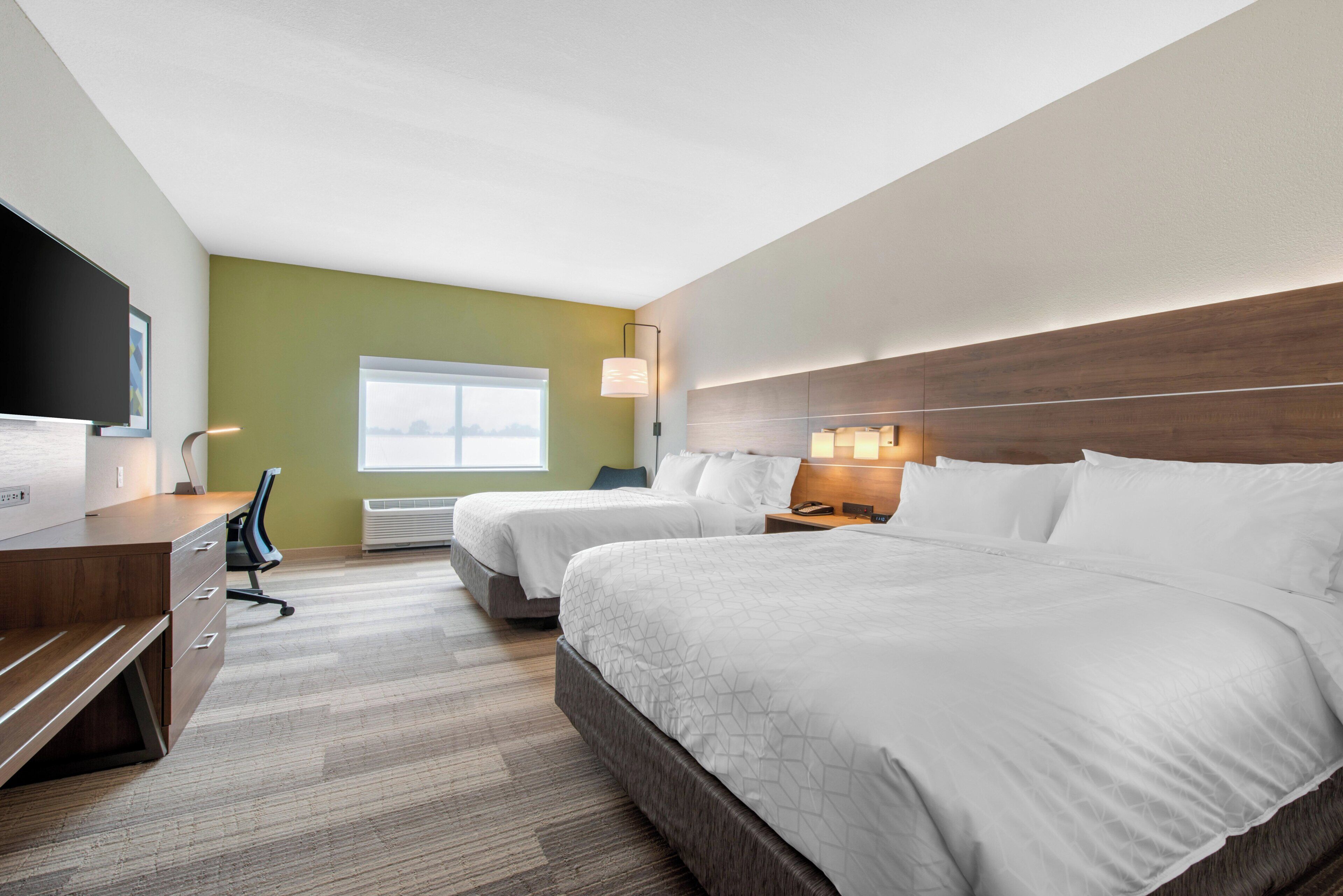 Une chambre d’hôtel avec deux lits, un bureau, une chaise, une télévision et une fenêtre donnant sur un beau paysage.