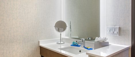 A bathroom with a white sink, a round mirror, and a large mirror above the sink.