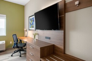 A modern office space with a wooden desk, a black office chair, a mounted flat-screen TV, and a framed abstract artwork on the wall. - Holiday Inn Express & Suites Alachua - Gainesville Area by IHG (Alachua)