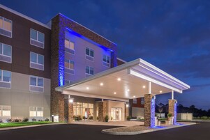 Un hotel con entrada cubierta, fachada de piedra y detalles de iluminación azul.