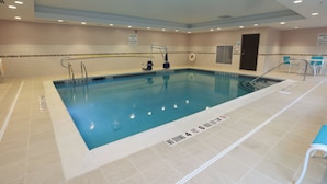 An indoor swimming pool with clear water, marked depth lines, and a lifeguard chair.