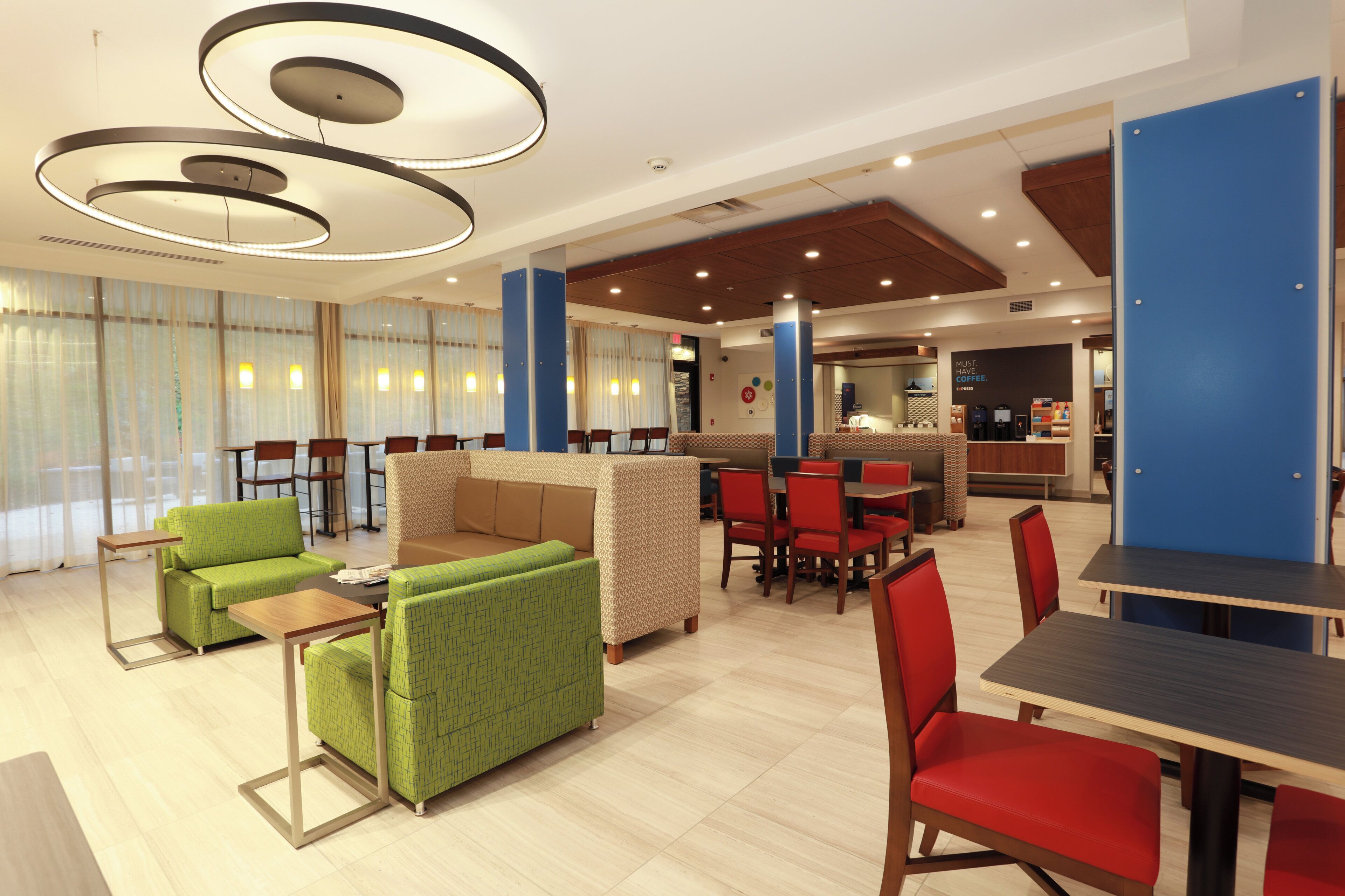 A modern hotel lobby with seating areas, a coffee bar, and a reception desk.