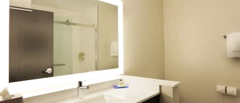 A modern bathroom with a large mirror, white sink, and a toilet.