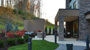 A modern building with a stone facade, outdoor seating area, and a landscaped garden.