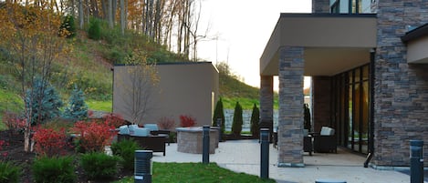 A modern building with a stone facade, outdoor seating area, and a landscaped garden.