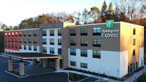 A Holiday Inn Express building with a modern design, featuring a mix of red and white facades, multiple windows, and a parking lot.