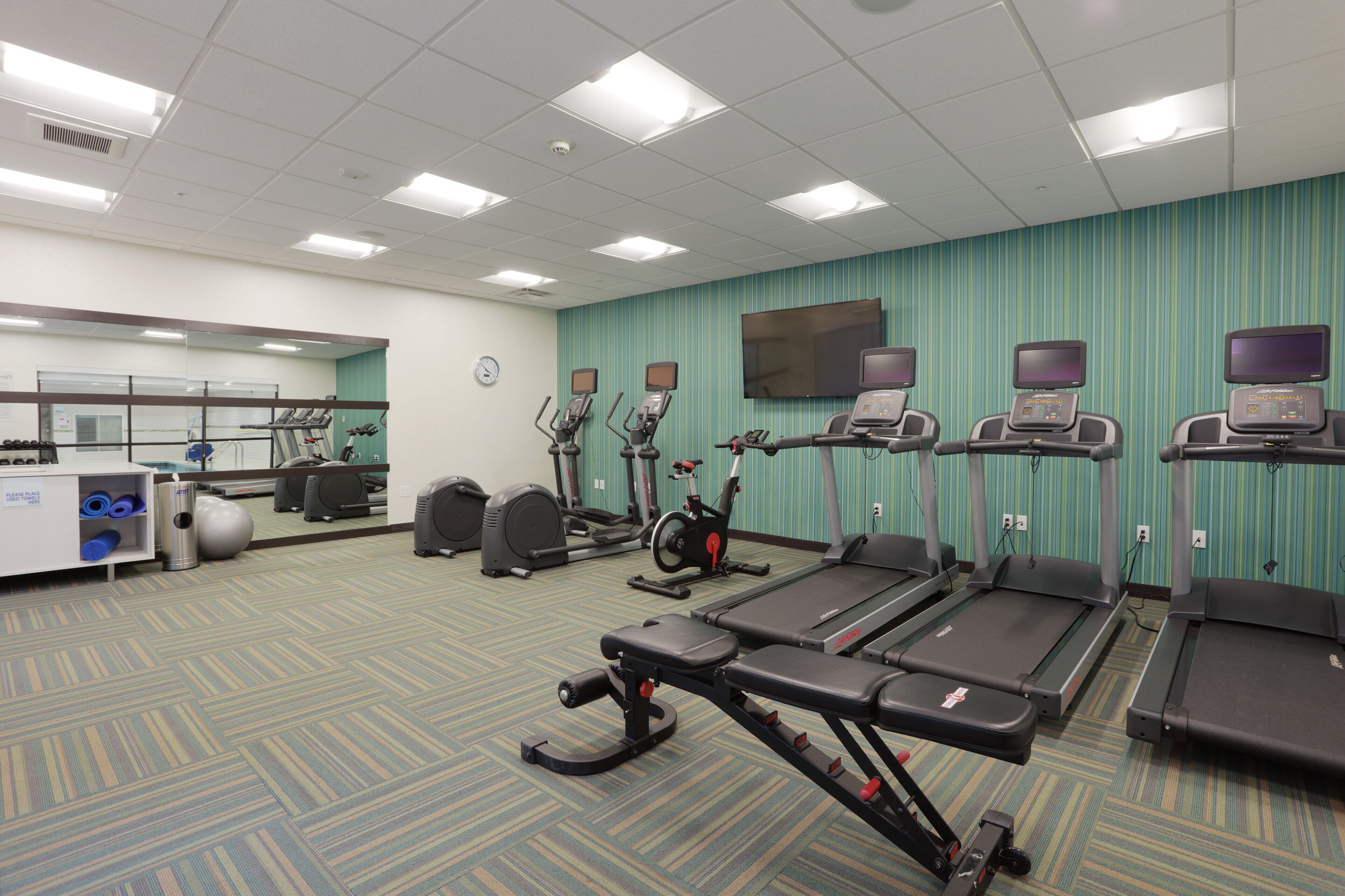 A fitness center with treadmills, elliptical machines, and exercise bikes.