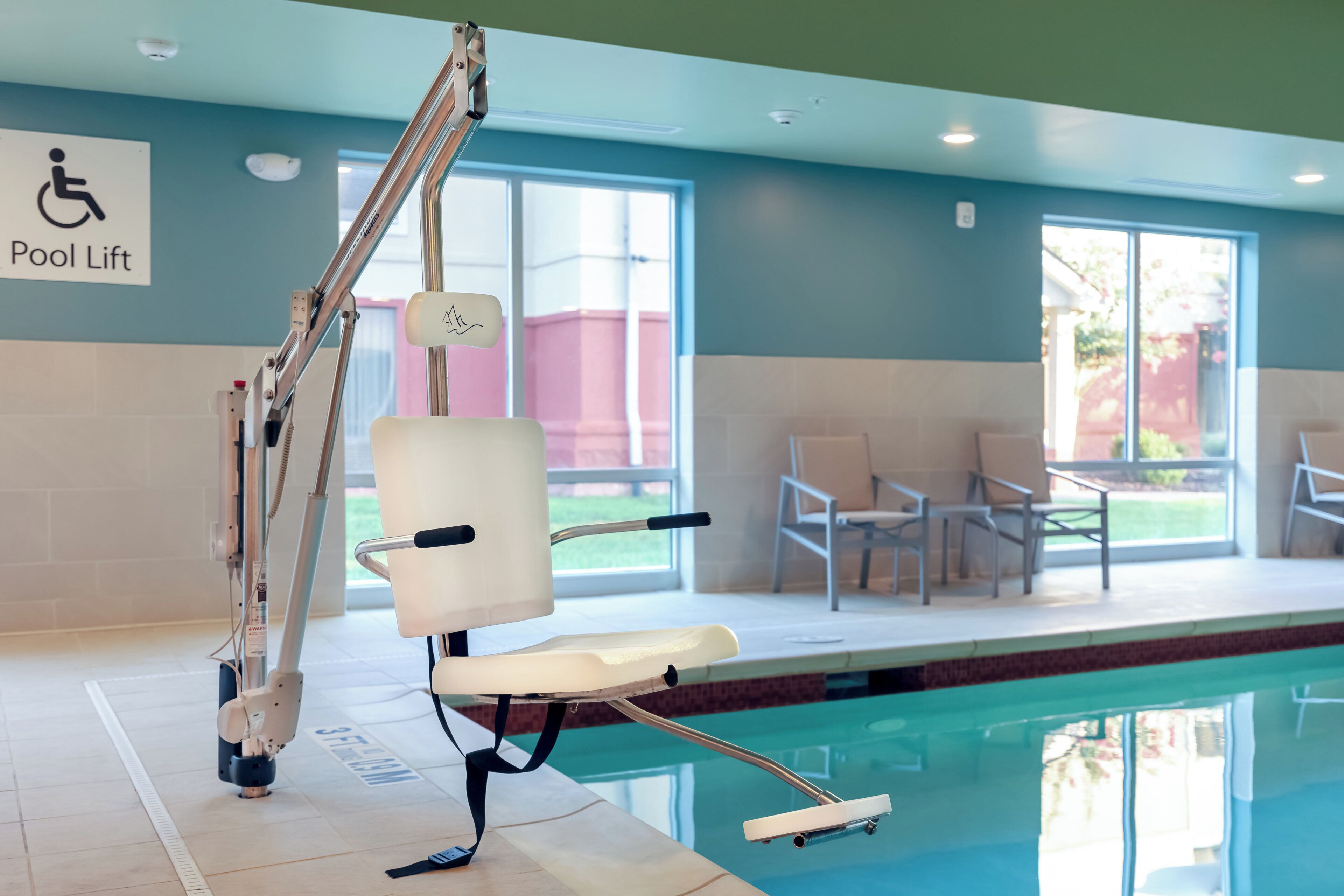 A pool lift chair by the poolside with a sign indicating a pool lift.