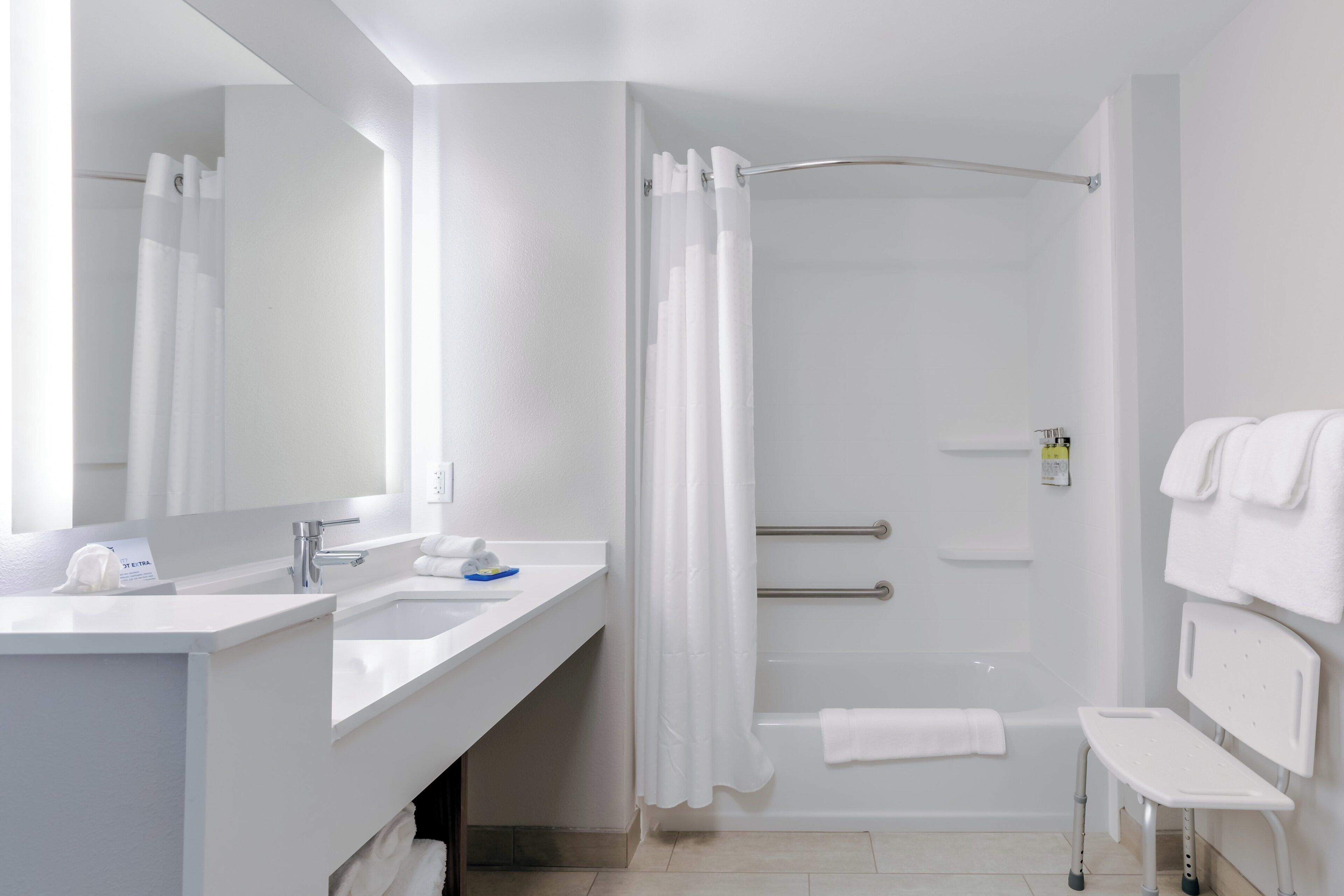 Een moderne badkamer met een douche, een wastafel met spiegel en een handdoekrek.
