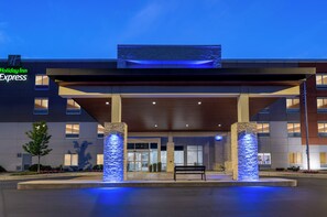 A Holiday Inn Express building with a covered entrance, stone pillars, and a bench in front. - Holiday Inn Express Calhoun South by IHG (Calhoun)