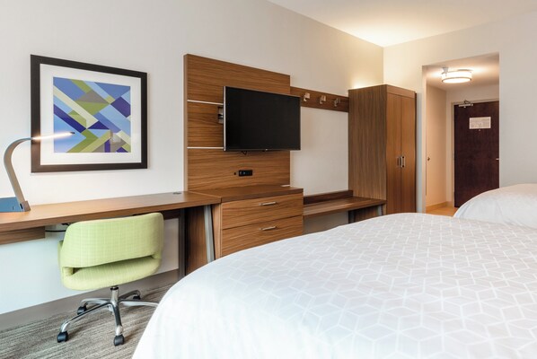 Une chambre d’hôtel comprenant un lit, un bureau avec une chaise, une télévision et une armoire.