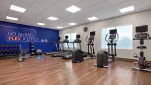 Ein Fitnessstudio mit Laufbändern, Crosstrainern und einer Wand mit motivierenden Texten.