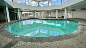 An indoor swimming pool with a clear view of the sky through the roof, surrounded by stone flooring and white walls. - 👣 Come get your toes in the sand. Lets make a splash! .🌊🐳🐬 (Gulf Shores)