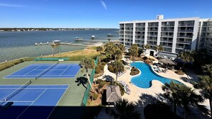 Hotel med swimmingpool, tennisbaner og udsigt over vandet.