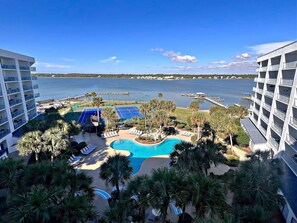 A resort with a swimming pool, tennis courts, and a view of the water.