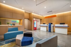A modern reception area with a counter, seating, and a vending machine. - Holiday Inn Express Sanya Bay by IHG (Sanya)