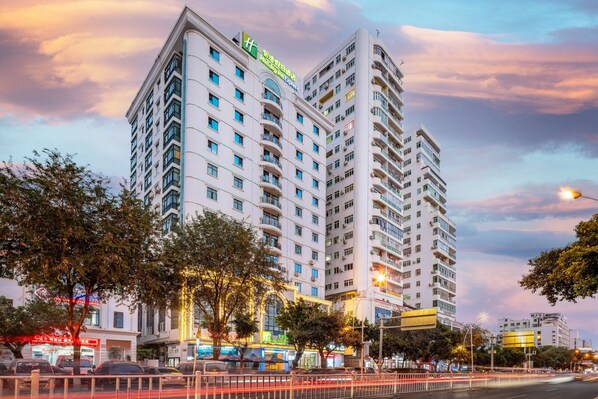 A multi-story hotel with a modern design, featuring balconies on each floor and a prominent signage indicating it is a hotel. - Holiday Inn Express Sanya Bay by IHG (Sanya)