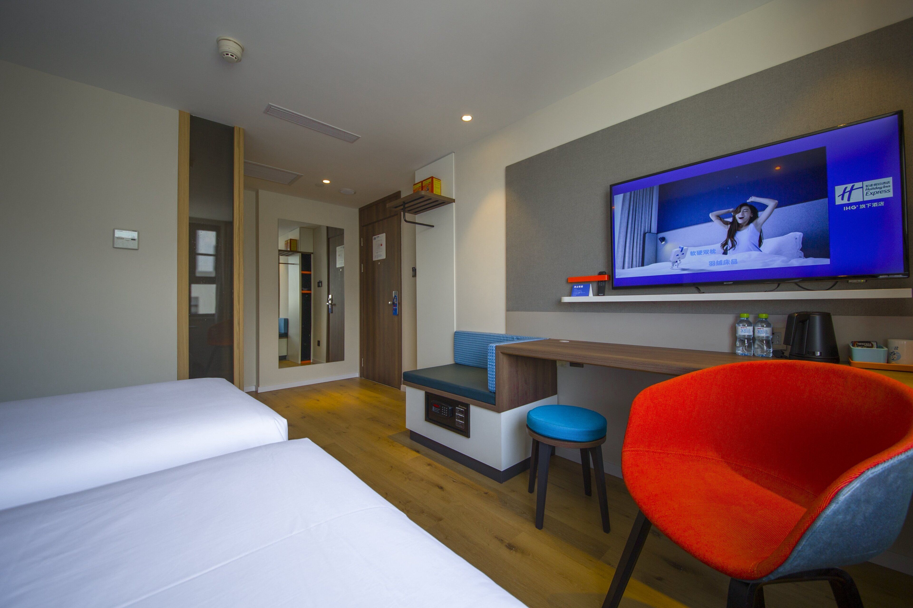 A hotel room with a bed, a desk, a television, and a chair.