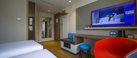 A hotel room with a bed, a desk, a television, and a chair.