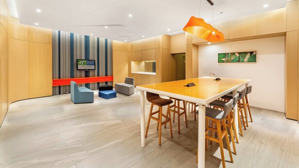 A modern meeting room with a wooden table, bar stools, a television, and a red accent wall. - Holiday Inn Express Sanya Bay by IHG (Sanya)