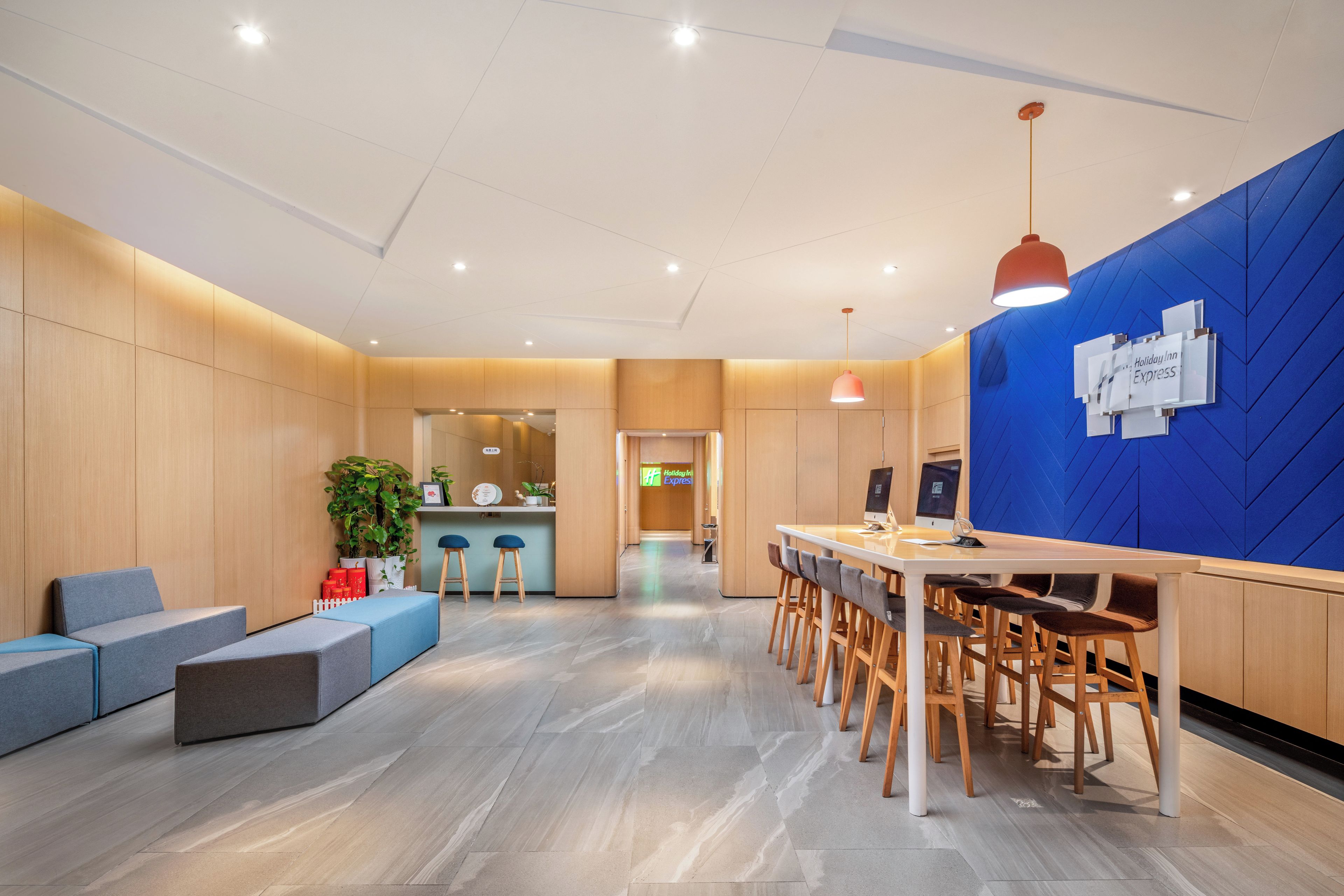 Una hall d'hotel moderna con una reception, un'area salotto e una parete azzurra.