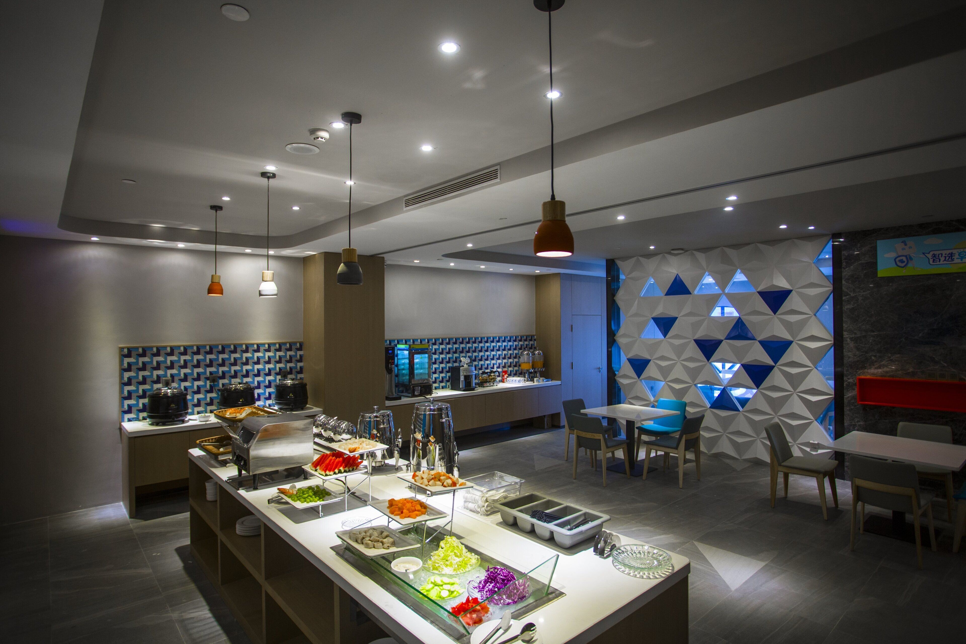 A modern cafe with a buffet, seating area, and a geometric wall design.