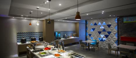 A modern cafe with a buffet, seating area, and a geometric wall design.