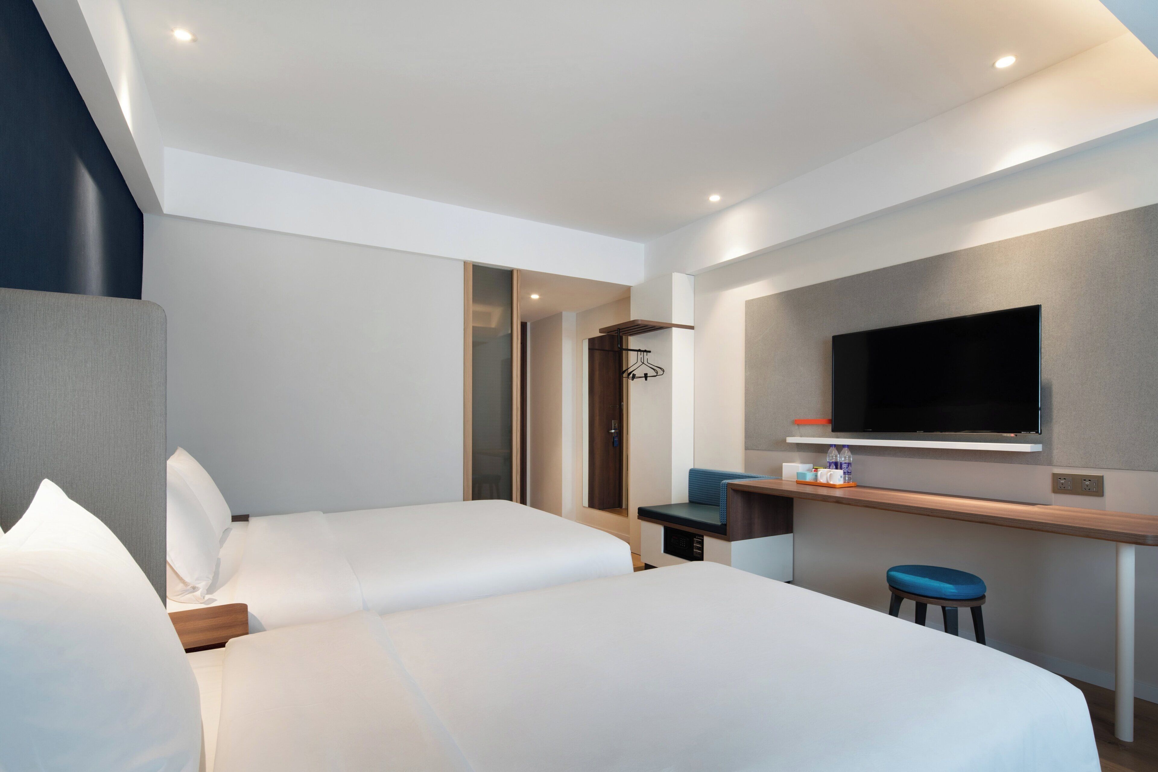 A hotel room with two beds, a TV, a desk, and a seating area.
