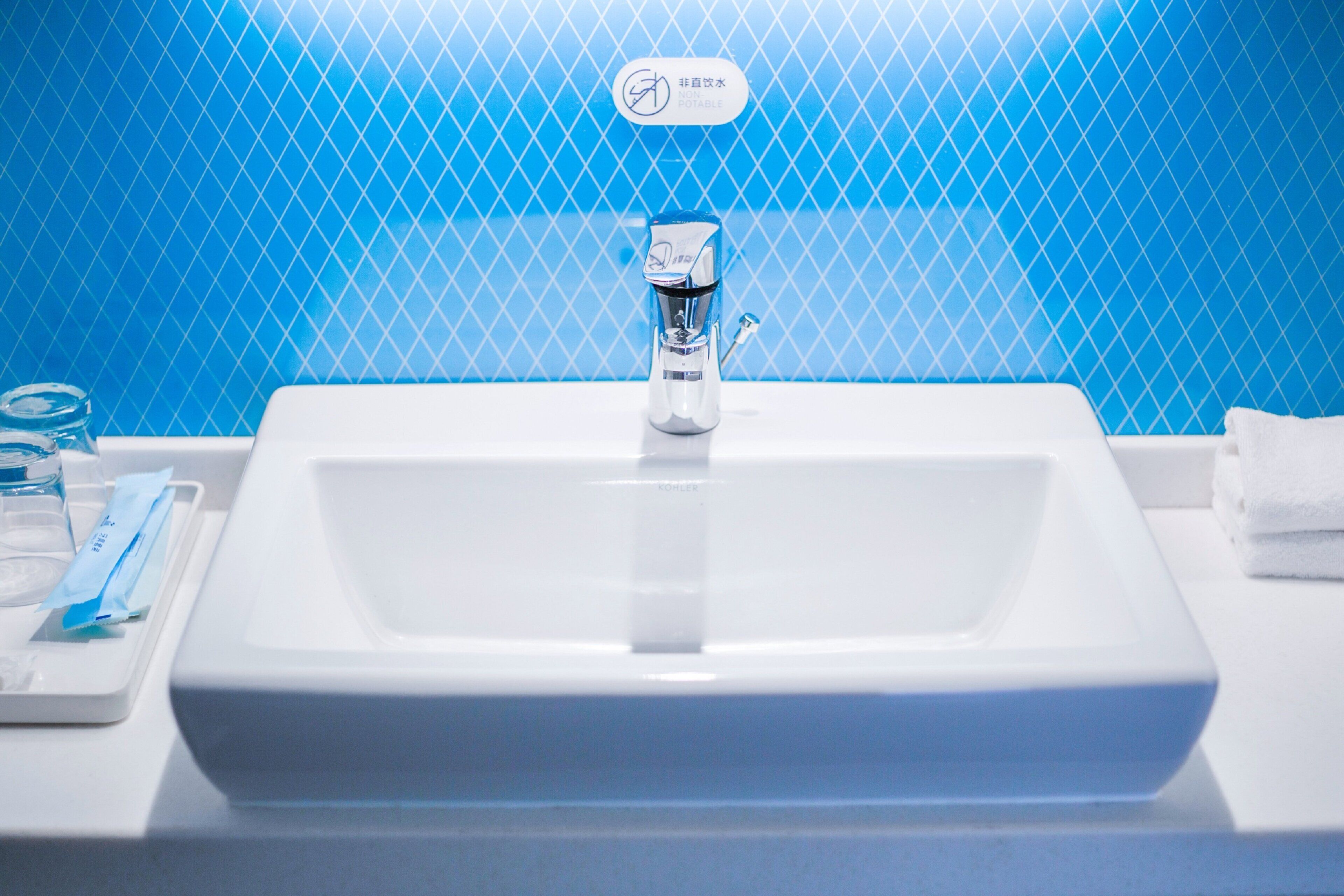 A bathroom sink with a faucet, a soap dispenser, and a towel stack.