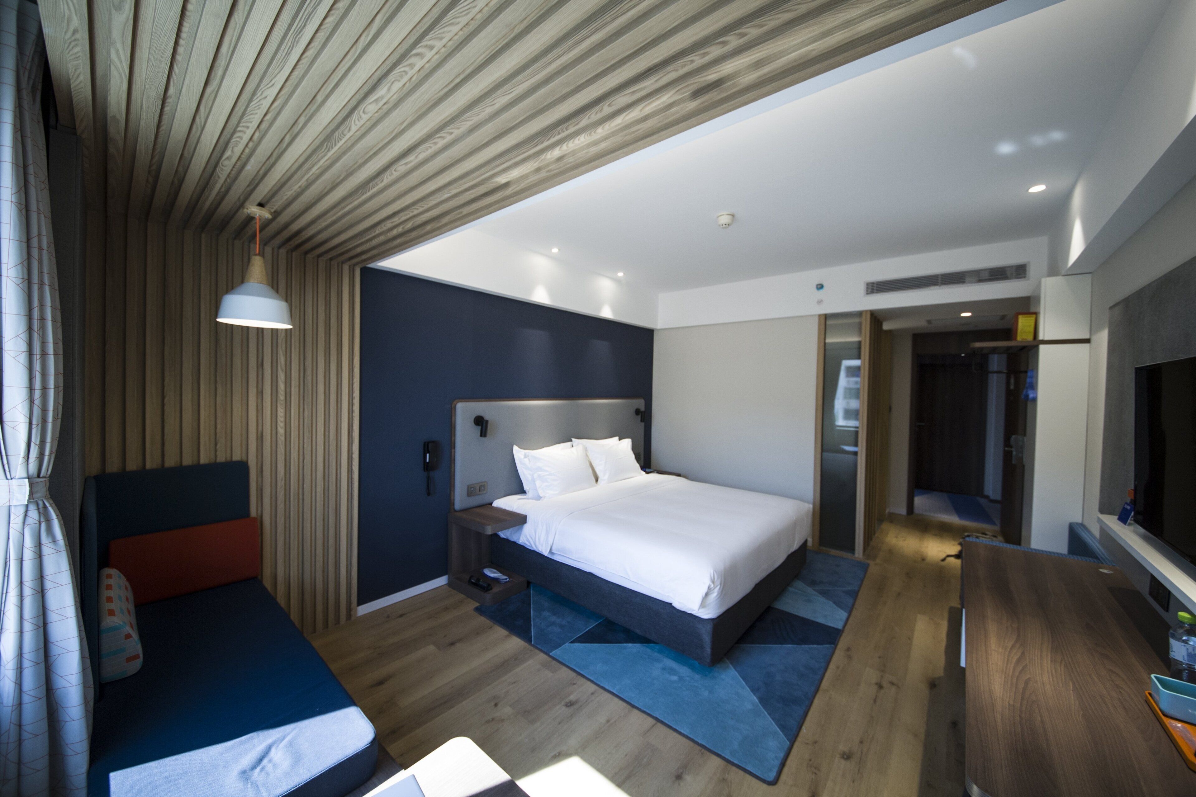 Et moderne hotelværelse med seng, sengebord og skrivebord med stol.