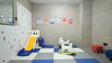 A children's play area with a slide, rocking horse, and colorful wall decorations.