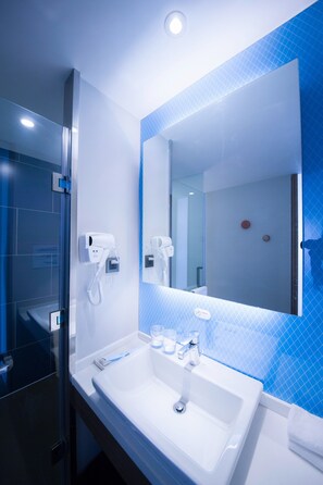 A modern bathroom with a white sink, a large mirror, and a hairdryer on the wall. - Holiday Inn Express Sanya Bay by IHG (Sanya)