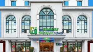 A Holiday Inn Express hotel with a white facade, large arched windows, and a prominent green logo. - Holiday Inn Express Sanya Bay by IHG (Sanya)