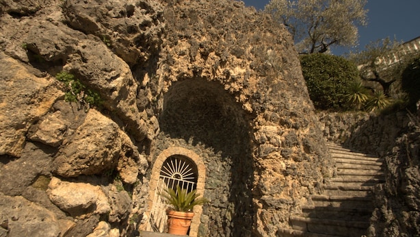 A stone staircase leading up to a doorway with a metal gate, surrounded by rocky terrain and vegetation. - La Villa Del Colle (Monte San Giovanni Campano)