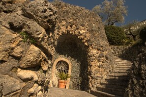 A stone staircase leading up to a doorway with a metal gate, surrounded by rocky terrain and vegetation. - La Villa Del Colle (Monte San Giovanni Campano)