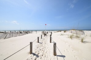 A sandy beach path leading to the ocean with a red flag marker. - Paradise is calling 🌴 Pick up! The beach is more affordable than you think! (Gulf Shores)