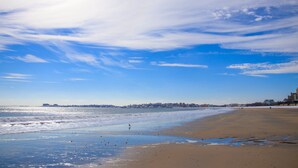 A beach with a clear sky, waves, and a distant shoreline with buildings. - Holiday Inn Boston Logan Airport - Chelsea by IHG (Chelsea)