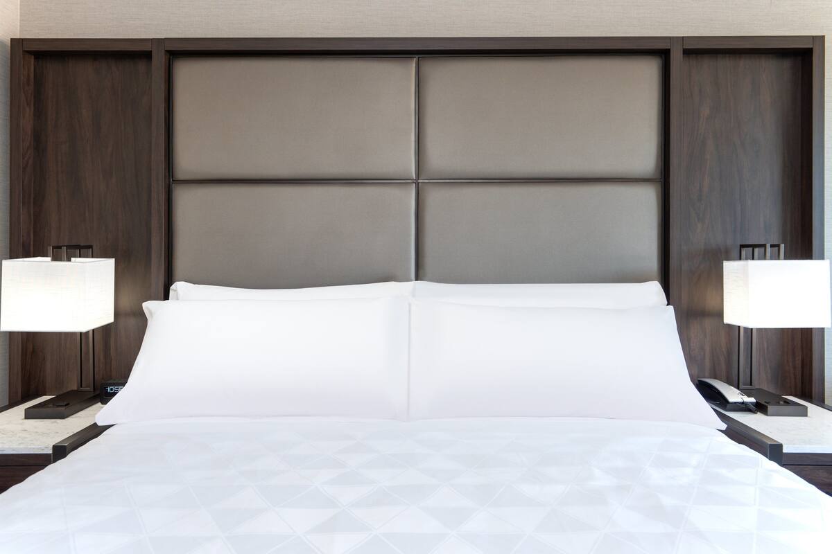 Ein Hotelzimmer mit einem großen Bett, zwei Nachttischen und einem Kopfteil mit Panelmuster.