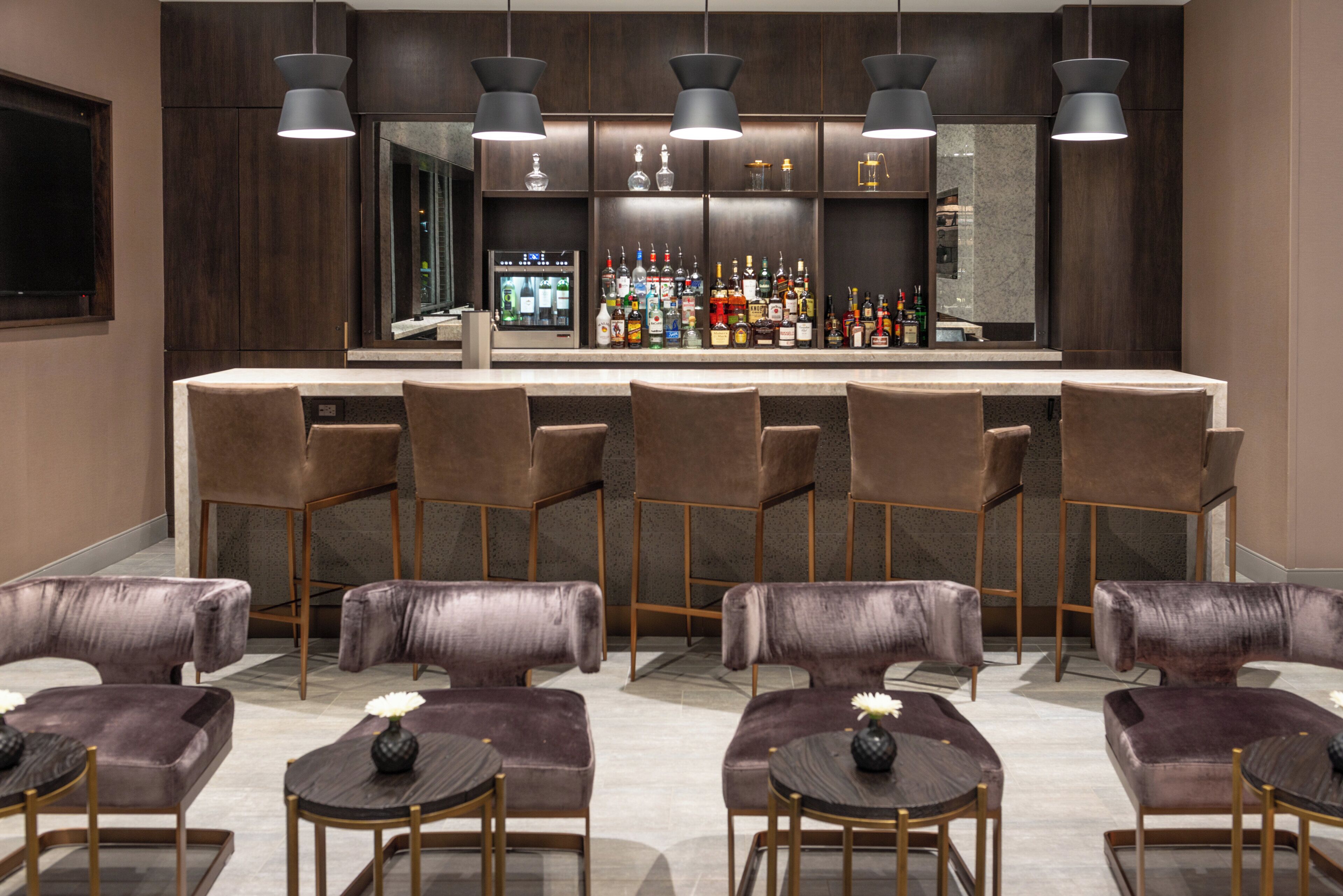 A bar area with multiple stools and a bar counter stocked with bottles.