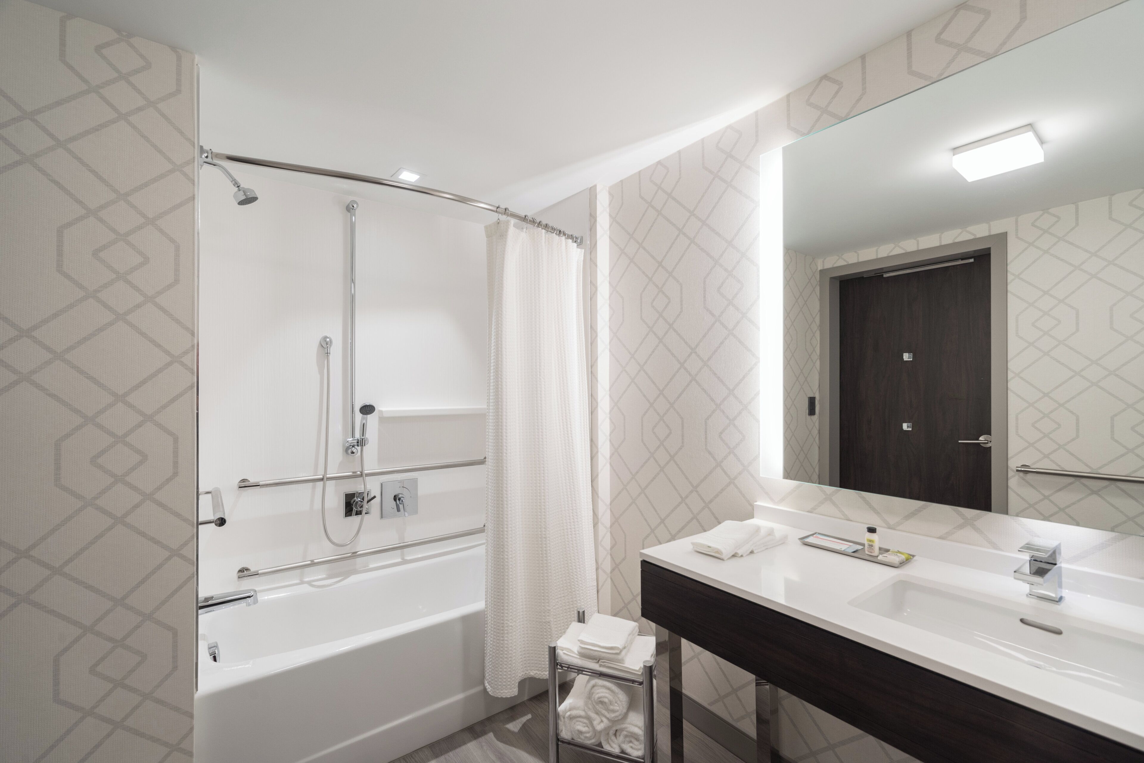 A modern bathroom with a shower, a sink, and a mirror.
