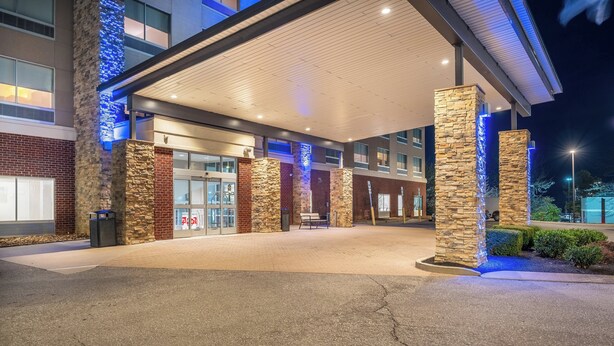 A modern building entrance with stone pillars, a covered walkway, and a parking area. - Holiday Inn Express & Suites Nashville North - Springfield by IHG (Springfield)