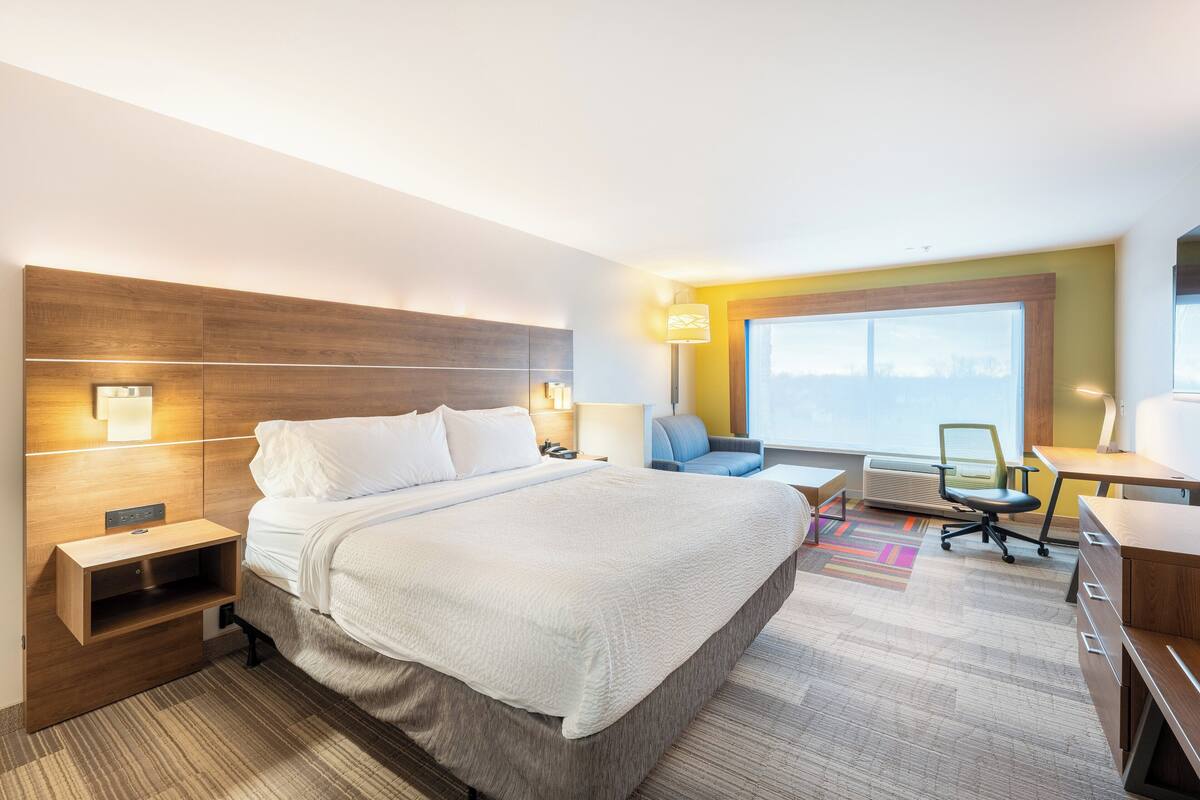 Una camera d'albergo con un letto grande, una scrivania, una sedia e una finestra vista.
