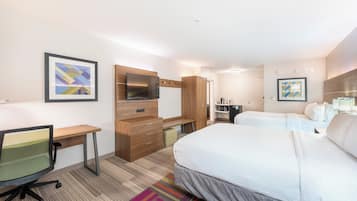 A hotel room with a bed, desk, chair, TV, and artwork on the walls.