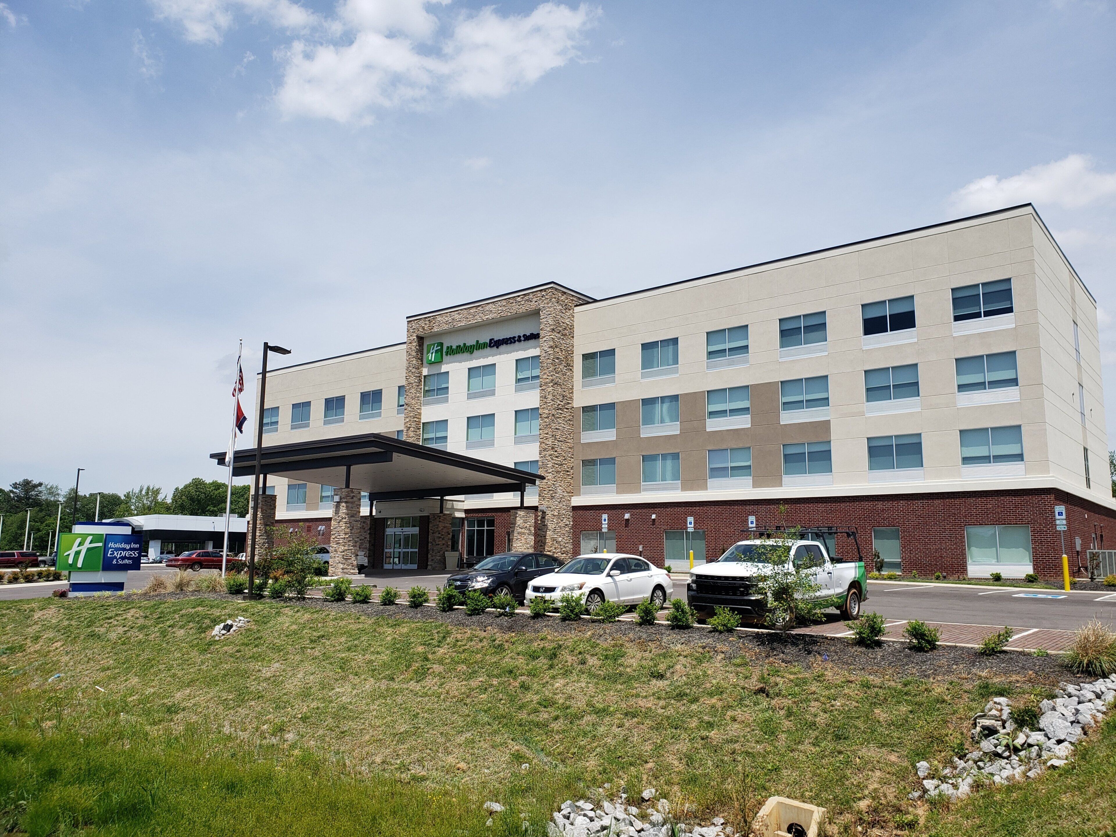 A Holiday Inn Express building with a covered entrance, multiple parking spaces, and a landscaped area in front.