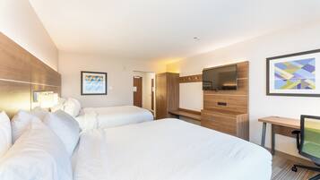 Habitación de hotel con dos camas, un escritorio, televisor y un cuadro en la pared.